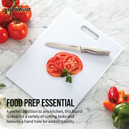 Cutting board with knife and sliced tomatoes, surrounded by fresh vegetables.