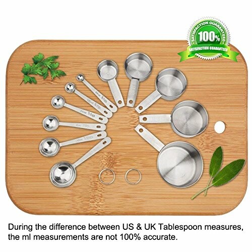 Set of metal measuring cups and spoons on a wooden board with herbs.