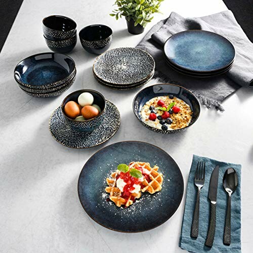 Modern dinnerware set with blue plates, bowls, and cups on a table with food.