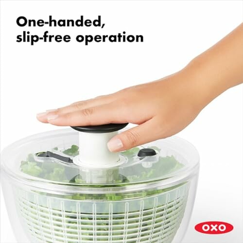 Hand operating OXO salad spinner with greens inside