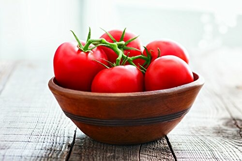 Ripe tomatoes in a wooden bowl on a table