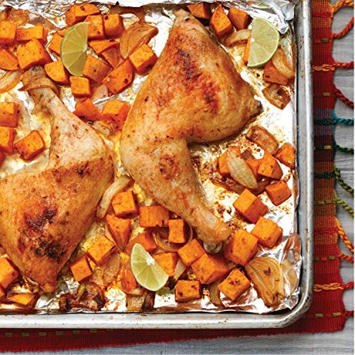 Roasted chicken legs with sweet potatoes and lime wedges on a baking sheet.