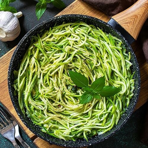 Pan of zucchini noodles garnished with basil.